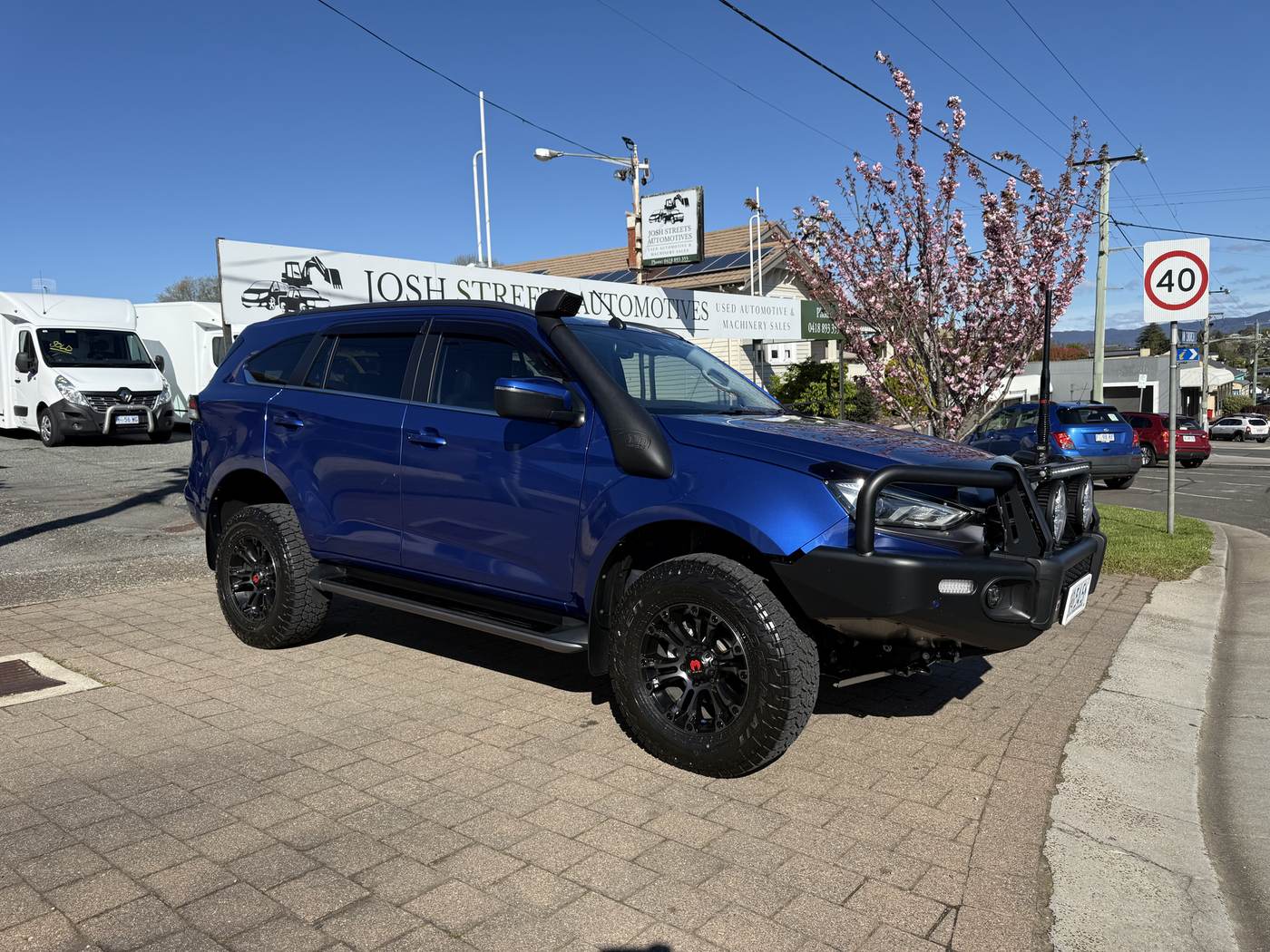 Blue Isuzu MU-X 4WD in front of the Josh Streets Automotives sign on Emu Bay Road, Deloraine